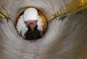 Man attempting to pass through a operational pipe.