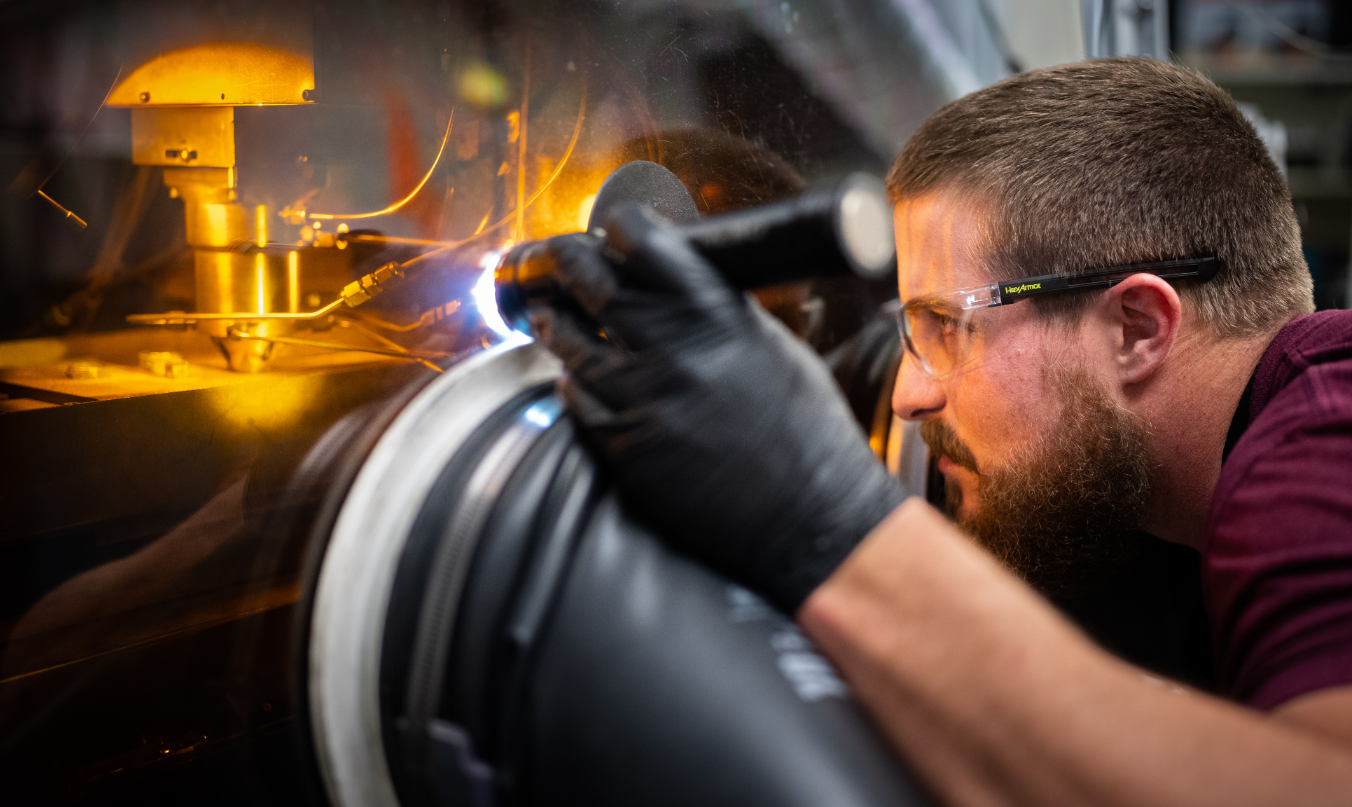 A technologist operates additive manufacturing equipment