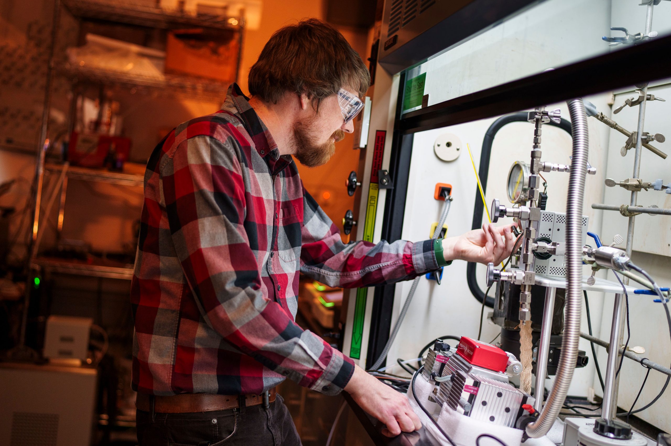 Matthew Paul, a Sandia National Laboratories geosciences engineer, works on a gas adsorption system in a fume hood as part of a project to see if depleted petroleum reservoirs can be used for storing carbon-free hydrogen fuel. (Photo by Craig Fritz)