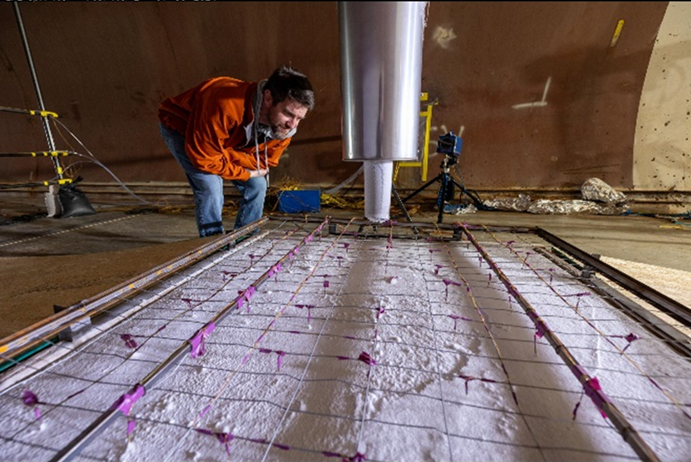 A researcher leans over a grid array that is covered in frost.