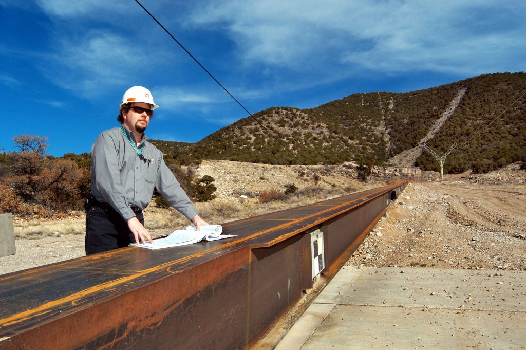 Scott Rowland, of Sandia’s planning organization, studies blueprints for work under way at the Labs’ Aerial Cable Facility. Plans at the site call for replacement of anchors, pulleys, sheaves, control winches, and a new rocket sled catch box.