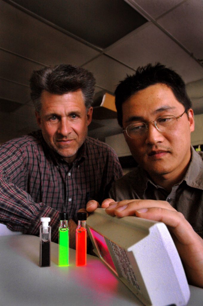 NOW, SIT UP: Jeff Brinker (left) and Hongyou Fan observe satisfactory fluorescence by their well-trained nanocrystals in water solution. The dark vial holds gold nanocrystals; the orange and green are semiconductor nanocrystals.