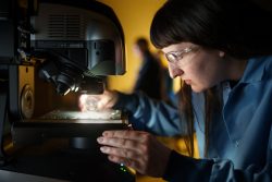 Woman holds an object under a mircoscope