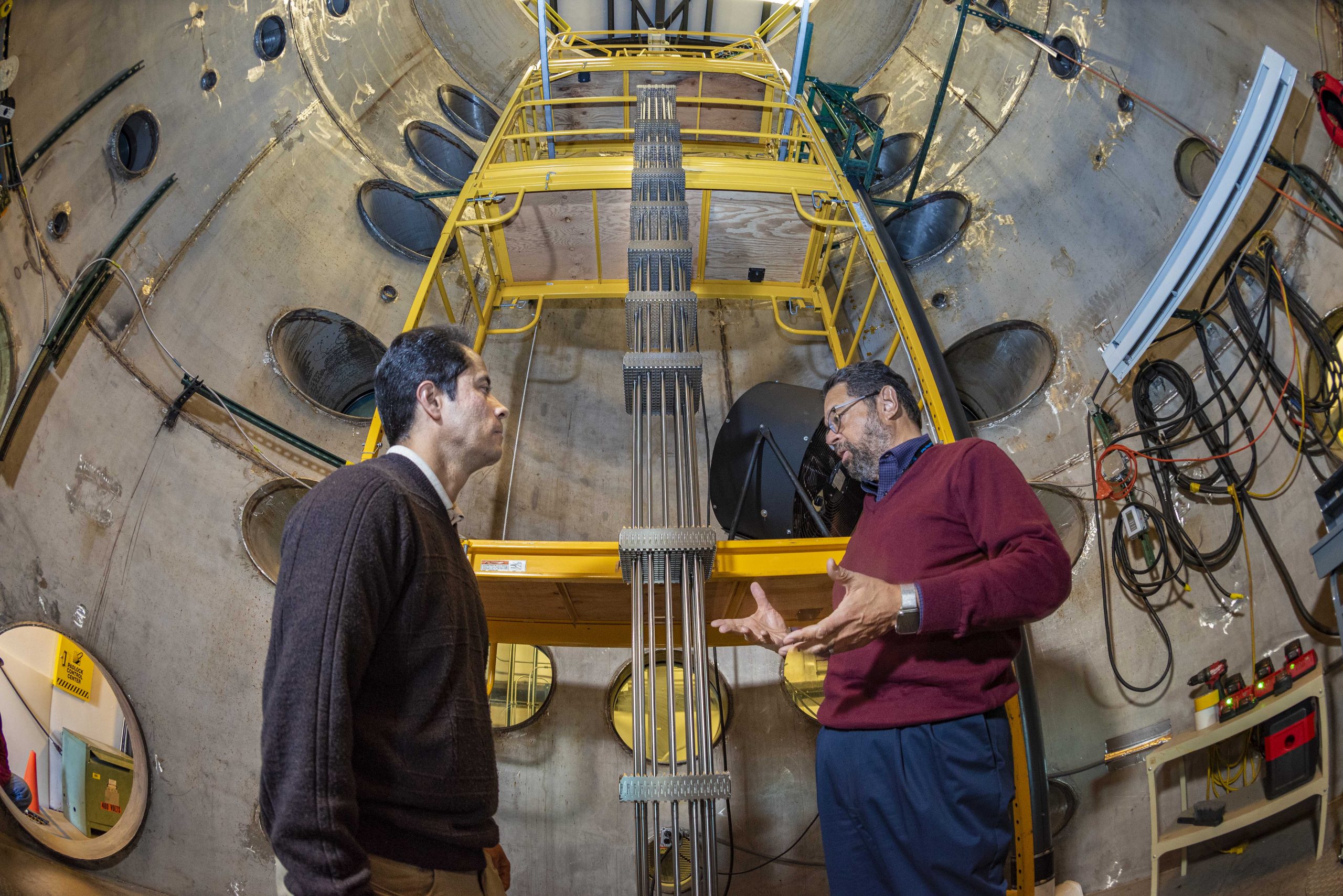 Tito Bonano stands with Efrain O’Neill inside a huge concrete cylinder with a yellow ladder.