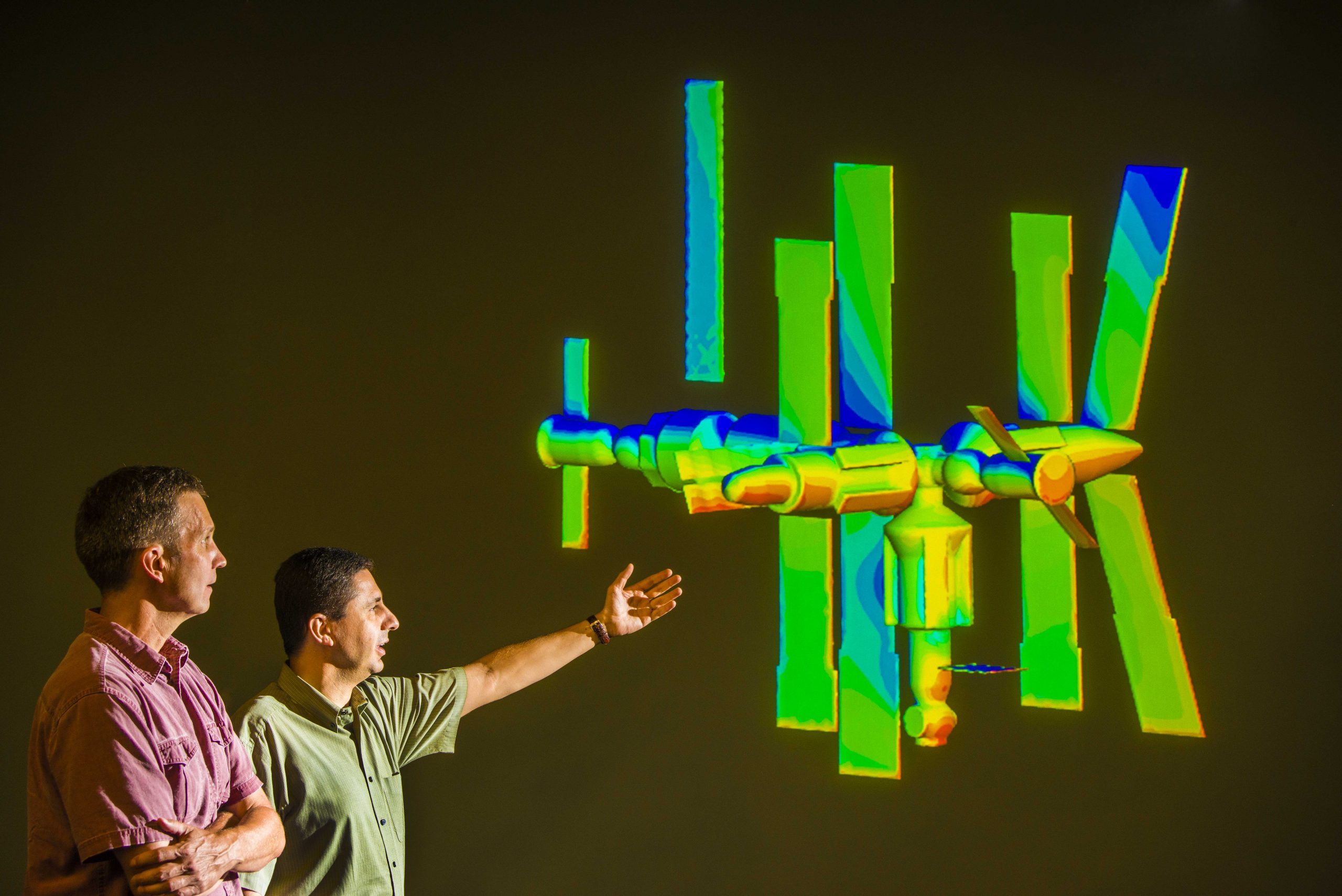 Sandia National Laboratories researchers Steve Plimpton, left, and Michael Gallis look at a projection of a model of the Russian MIR space station, which fell out of orbit several years ago and disintegrated, with the remains ending up at the bottom of the Indian Ocean. Using Sandia's 3-D code SPARTA, the calculation is simulating an instance of the process of de-orbiting.