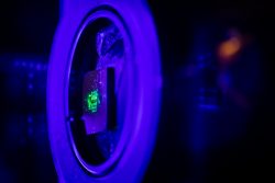 A small, flat surface glows green, mounted to a circular laboratory apparatus.