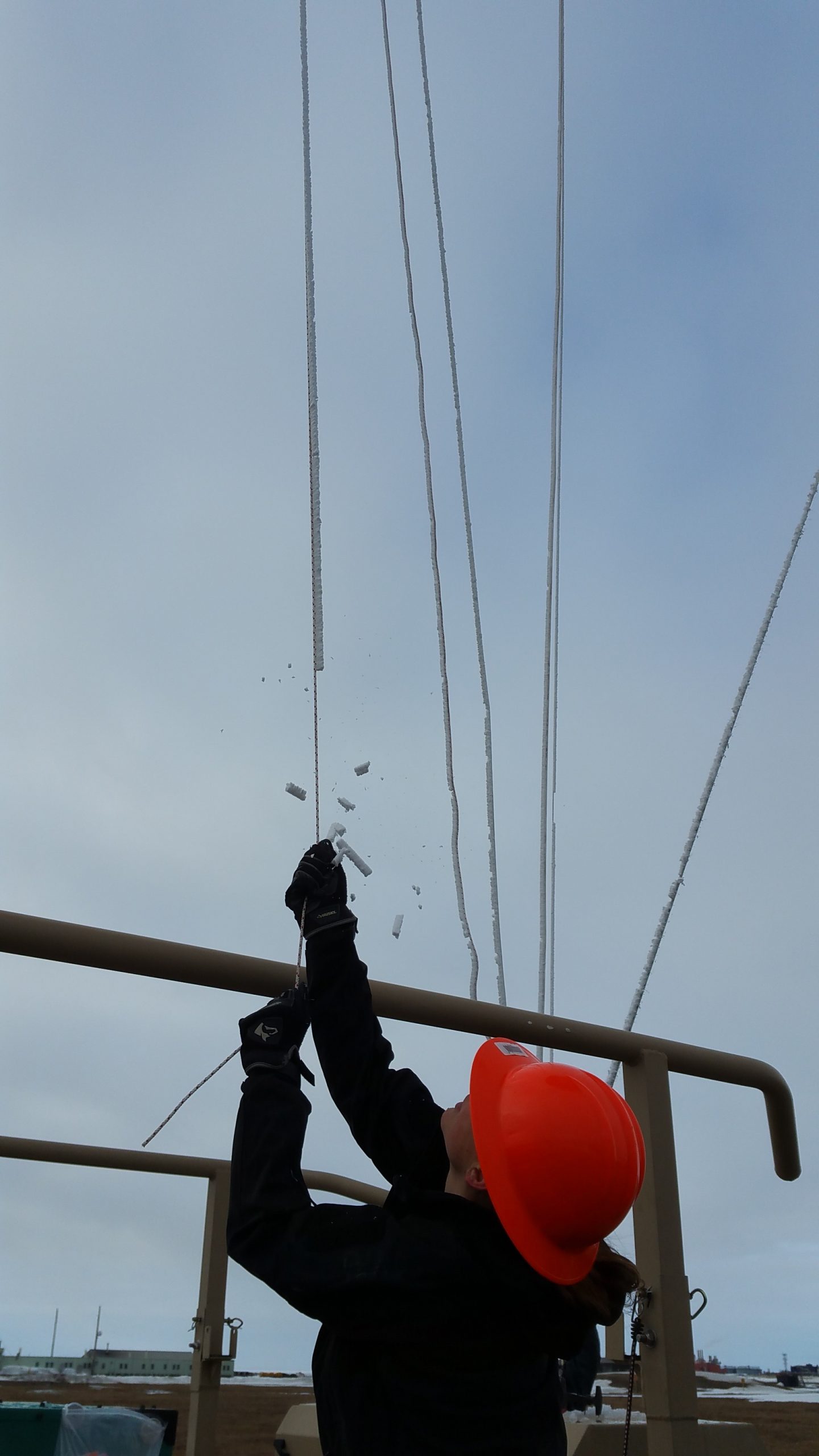 Ice pops from a balloon's tether line as Sandia National Laboratories researcher Darielle Dexheimer gathers in an instrumented balloon at the Atmospheric Radiation Measurement research station at Oliktok Point, Alaska. The balloon is about 25 feet above Dexheimer's head and the lines are completely iced over.