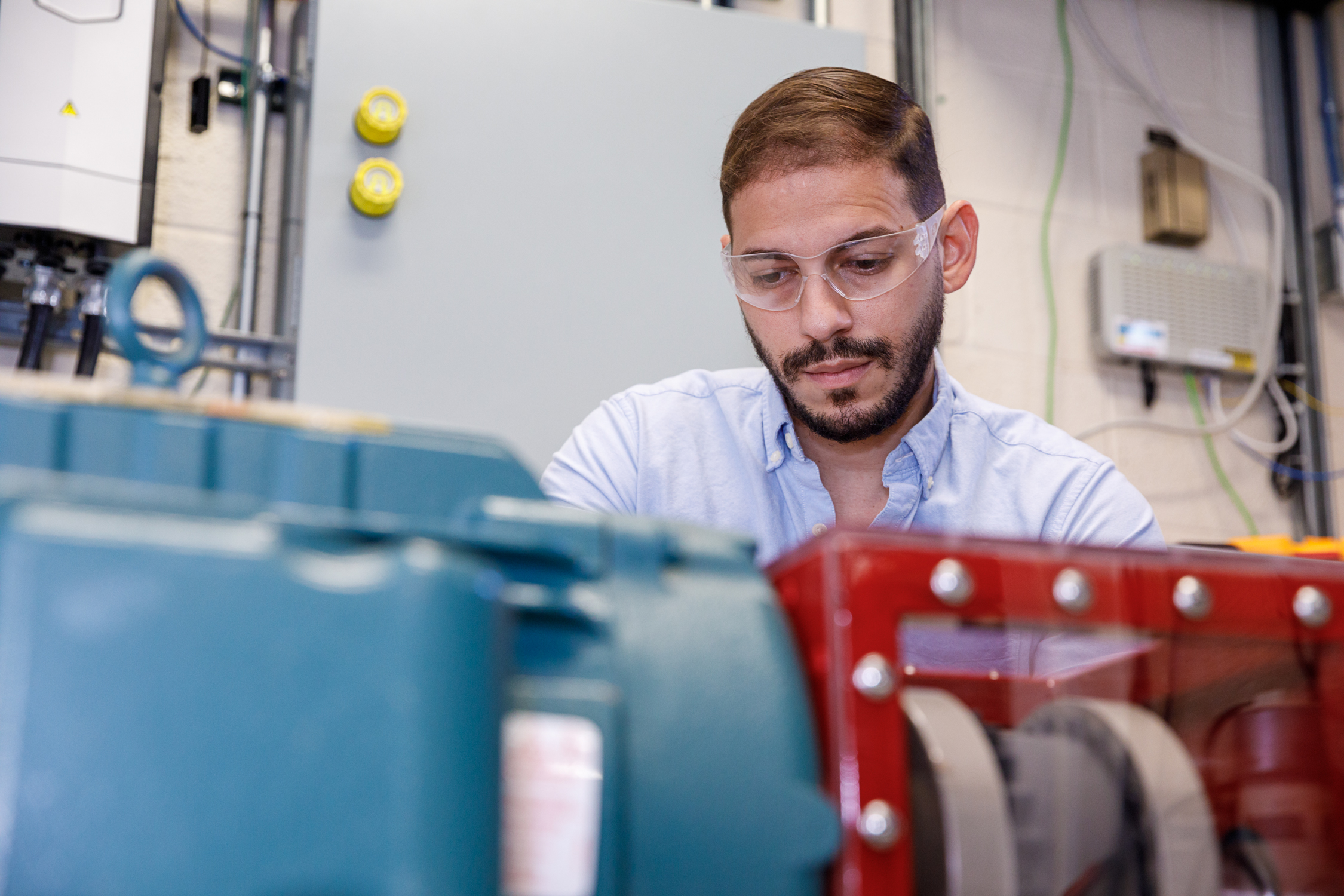 Scientist in protective gear looks at a cyan and red couston-built wind turbine emulator