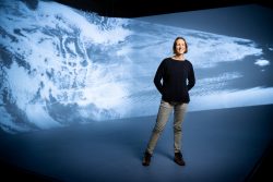 Woman stands before image of clouds