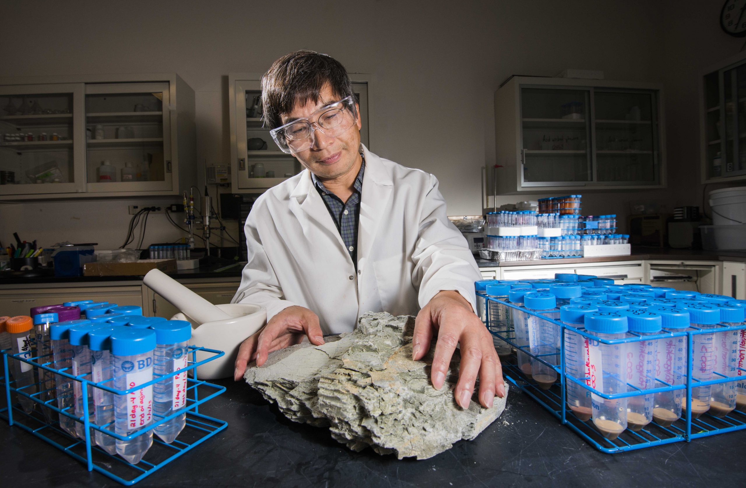 Sandia researcher Yifeng Wang examines a clay sample from South Dakota as part of iodide experiments. A team of Sandia researchers is working to understand how fast iodine-129 released from spent nuclear fuel would move through a deep clay-based geological repository.