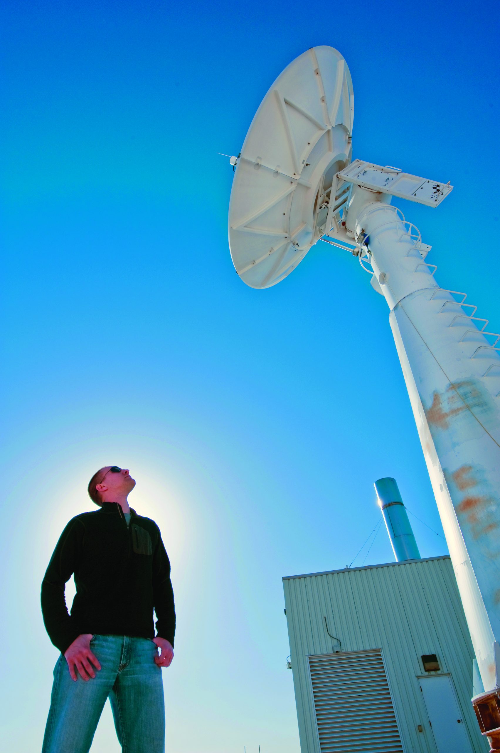 Brian Post stands under an antenna at the ground station at Sandia National Labs during the MTI satellite’s 55,000th orbit (photo by Randy Montoya).