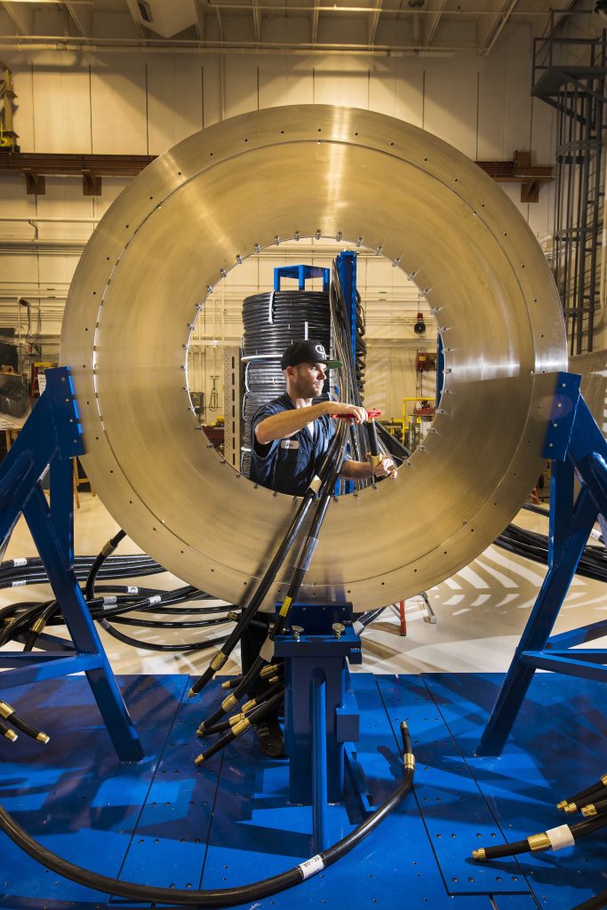 MAKE READY FOR THOR — Sandia National Laboratories technician Eric Breden installs a transmission cable on the silver disk that is the new pulsed-power machine’s central powerflow assembly. (Photo by Randy Montoya) Click on the thumbnail for a high-resolution image.