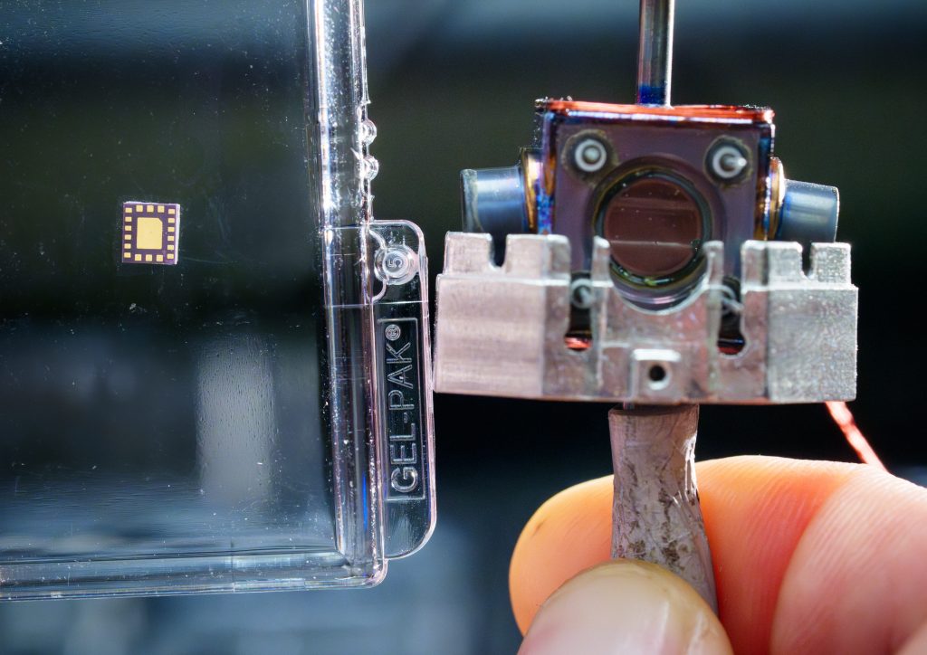 A miniature laser package for housing multiple 455 nanometer VCSELs, left, and a 3 cubic centimeter vacuum package for trapping and interrogating ions, right, are two critical components required for a buffer-gas-cooled microwave ion clock at Sandia National Laboratories. (Photo by Craig Fritz) Click on the thumbnail for a high-resolution image.