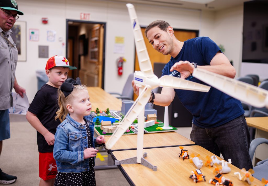 Sandia National Laboratories electrical engineer Rachid Darbali-Zamora, right, shows the power of renewable energy and the microgrid to Alex Riebli and his children Mason, 7, and Addison, 4. Darbali-Zamora has been honored with a Luminary Award by Great Minds in STEM for his technical achievements. (Photo by Craig Fritz) Click on the thumbnail for a high-resolution image.