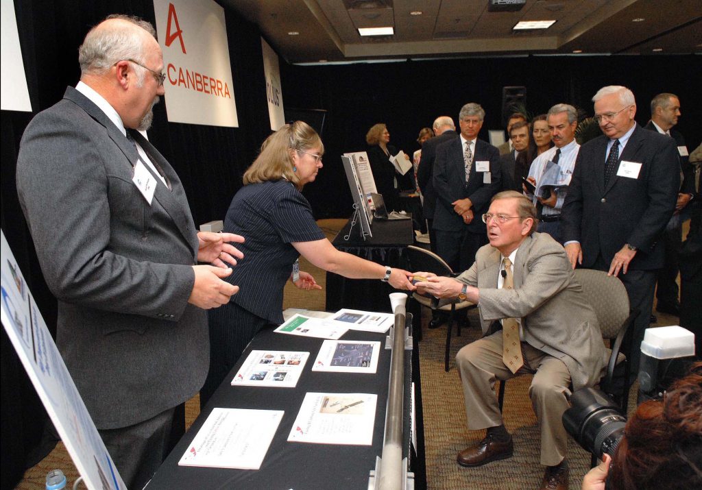 Sen. Pete Domenici, R-N.M., receives a briefing at a recent Sandia event by Gloria Chavez and Randy Normann about the HTSS10V high-temperature batteries for deep oil exploration.