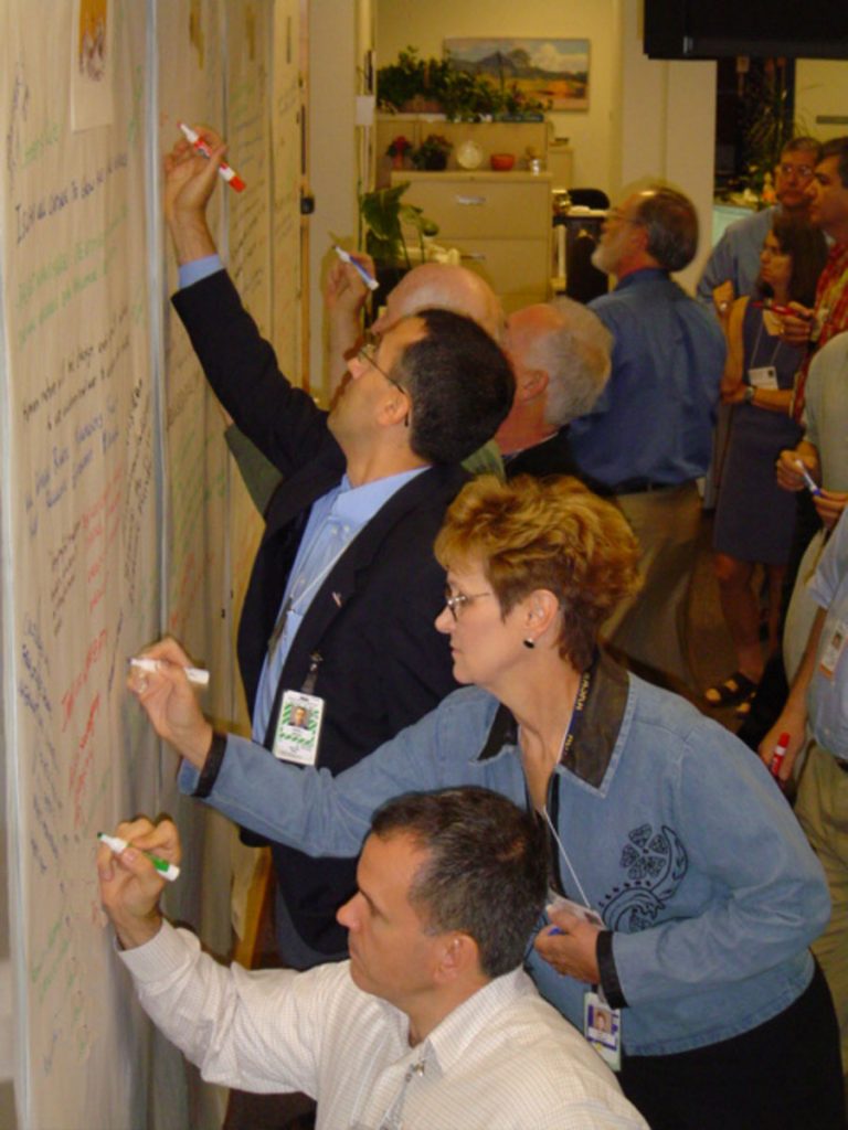 Future of War Think-Fest participants write their ideas on a large white board.