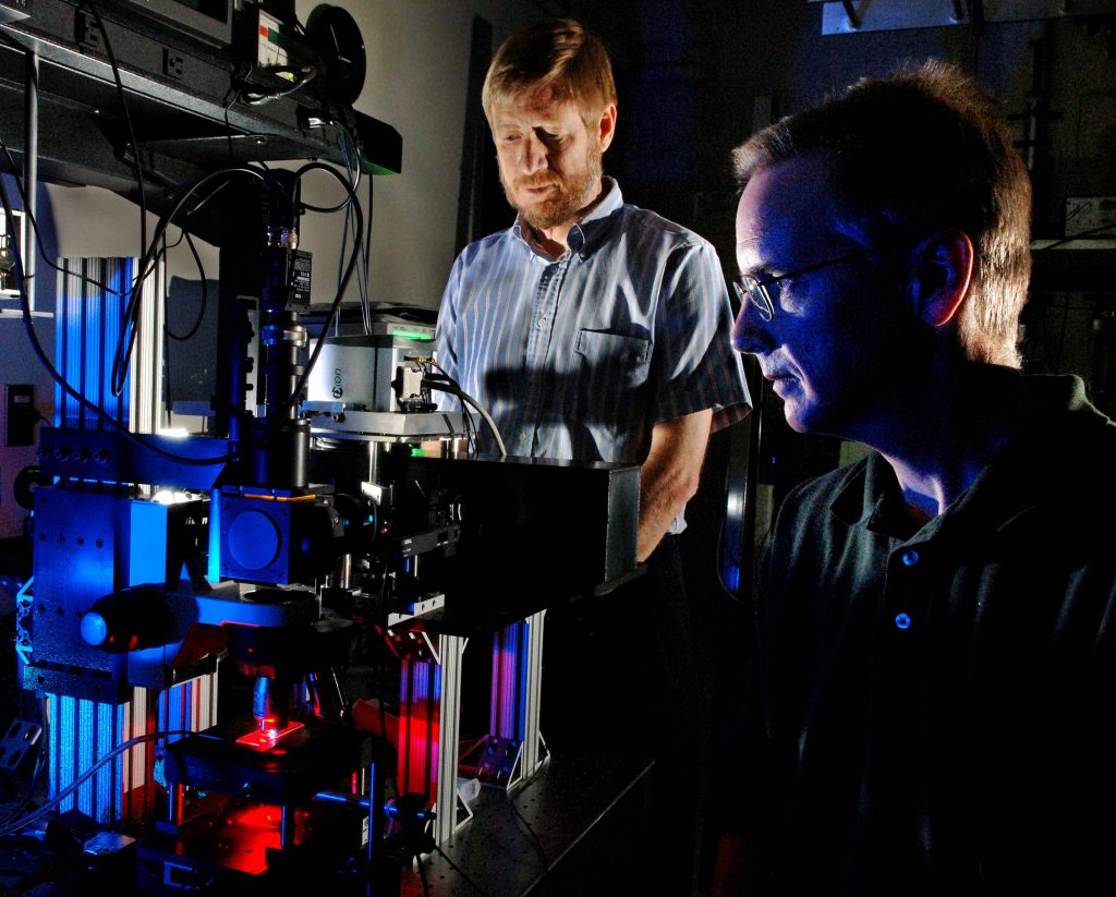 Sandia National Laboratories researchers Michael Sinclair (foreground) and David Haaland prepare a hyperspectral confocal microscope for measurement of a biological specimen. The new microscope, shown on the left, was designed and fabricated at Sandia and is expected to be used by Monsanto to enhance the company's current crop analytical technologies.