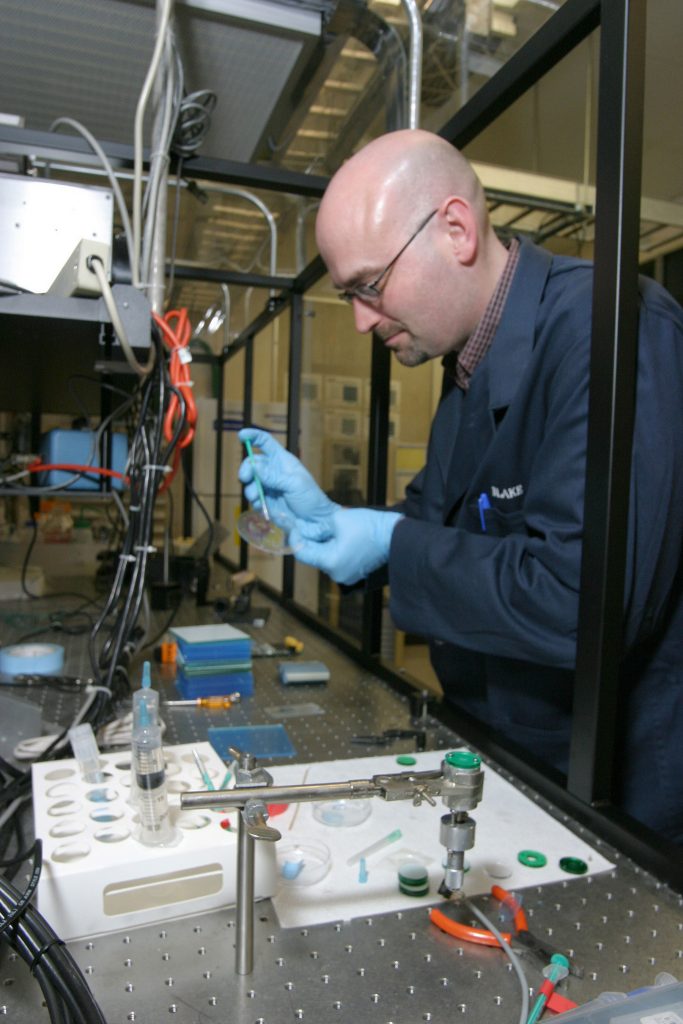 Sandia researcher Blake Simmons prepares a polymer microfluidic device — known as iDEP — for use as a particle concentrator. iDEP can deliver detectable amounts of material in small sample volumes, eliminating any need for overnight culturing and significantly speeding up overall water analysis.