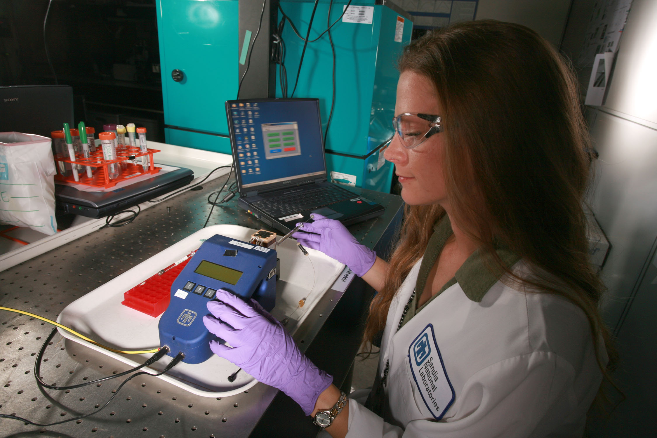 Sandia researcher Amanda Jokerst injects a sample into a handheld microseparations platform for analysis. Jokerst and others at Sandia aim to optimize the micro-separations process for a sub-set of relevant toxins found in harmful algal blooms (HABs) and establish the laboratory-based protocols for sample preparation.