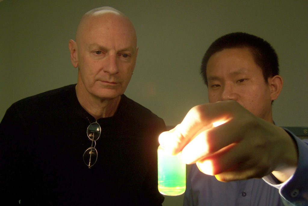 GLOWING PORPHYRIN NANOTUBES -- Sandia researchers John Shelnutt and Zhongchun Wang gaze upon the glow of porphryin nanotubes caused by the nanotubes’ intense resonance light scattering activity.