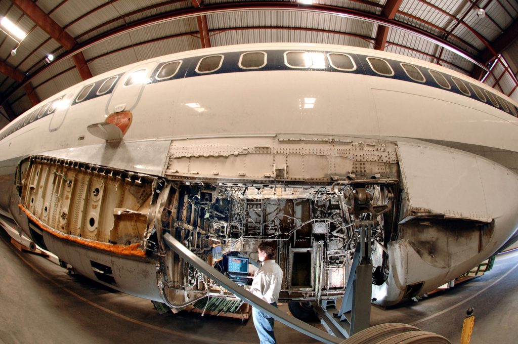 Sandian Kevin Howard inspects electrical wiring in the wheel well of a retired Boeing 727 at Sandia’s FAA Airworthiness Assurance NDI Validation Center. The wing on the 727 has been removed.