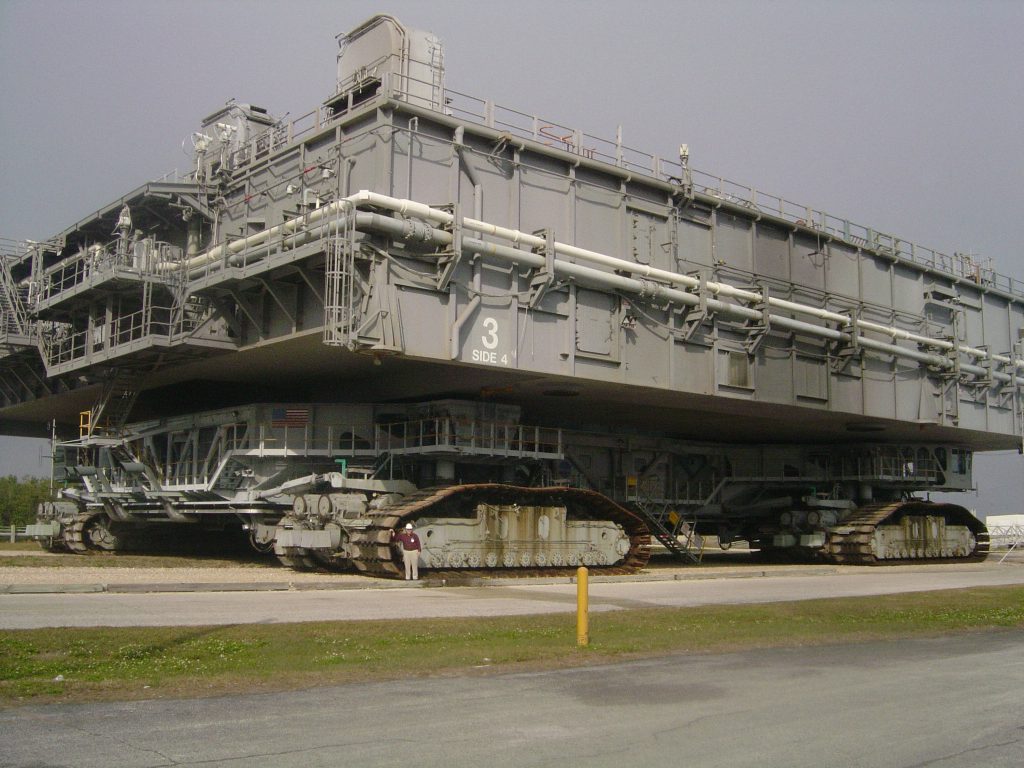 Tom Carne stands in front of NASA’s massive mobile launch platform and the crawler that carries the space shuttle from Kennedy Center’s Vehicle Assembly building to the shuttle launch pad.