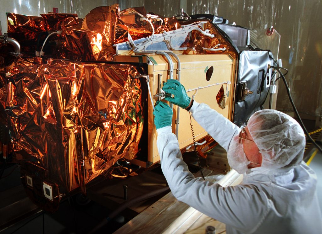 Gary Webb of Sandia National Laboratories makes some final payload checks on the Sandia-integrated Multispectral Thermal Imager satellite, seen here without its four fold-out solar panels.