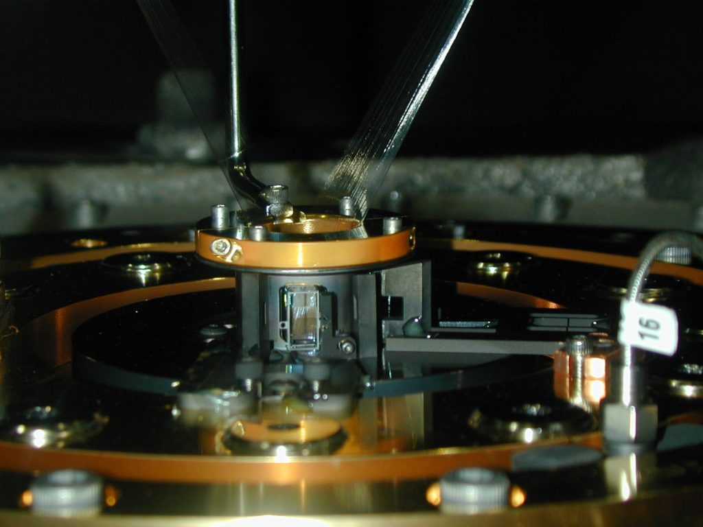 THE BLACK HOLES AMONG US -- In front of a containment can at the center of Sandia's Z machine, a small window-like frame holds a shining foil containing a layer of mixed iron and sodium fluoride only 500 Angstroms thick, sandwiched between two micron-thick plastic substrates. Just after Z reaches peak power, the iron inside the foils reaches conditions normally only found in the immediate vicinity of neutron stars and black holes, where streams of infalling matter are vaporized by x-rays driven by the immense gravitational power of these compact objects. At Z, a spectrometer measures the absorption of Z's X-rays by the face-on iron foil, and the emission of X-rays from the edge-on foil. Sodium fluoride provides a temperature correlation. The hard data will be used by astronomers trying to understand how extreme conditions affect iron -- a complex element widespread in the universe -- in images returned by Chandra and two other soon-to-be-orbitted billion-dollar X-ray telescopes.