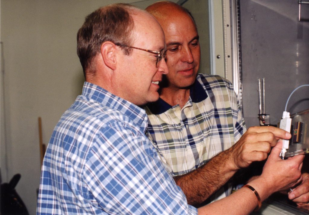 NEW APPROACH — Sandia researchers Charles Barbour, left, and Jeff Braithwaite prepare a combinatorial corrosion experiment on a single silicon wafer. The new experimental method promises to shed light on how and why copper corrodes in atmospheric environments.