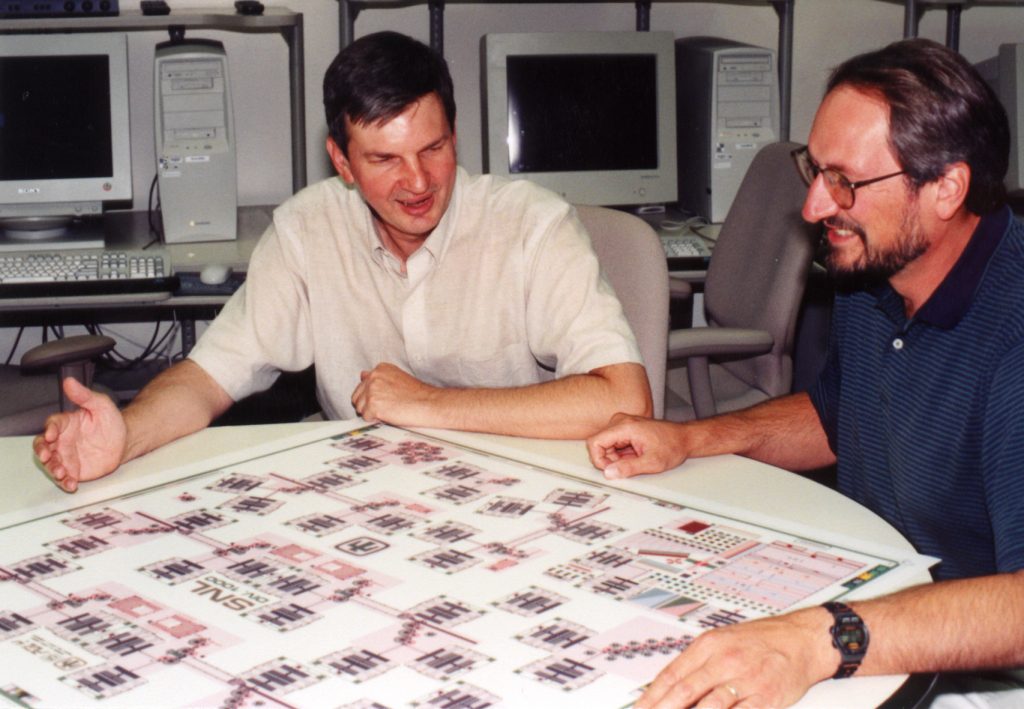 SANDIA'S STEVE RODGERS (left) and Jeff Sniegowski look over a computer schematic of a five-level polysilicon surface micromachine.