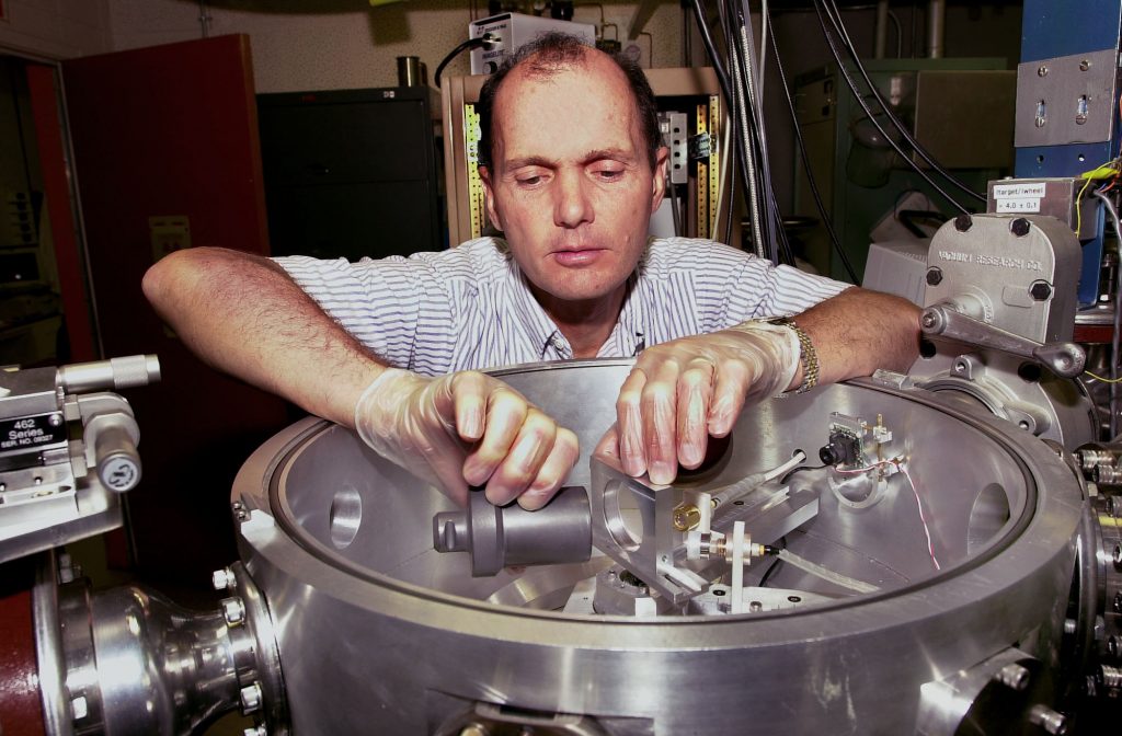 EROSION MEASUREMENT — Sandia researcher Bill Wampler places a graphite sample that was exposed to divertor plasma into a chamber for ion-beam analysis to measure the erosion.