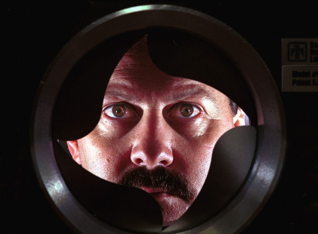 BETTER DETECTORS -- Kevin Linker of Sandia National Laboratories looks through the air-intake/valve assembly of a Sandia chemical preconcentrator. By miniaturizing the basic preconcentrator technology, the researchers are creating hand-carried "sniffers" that can detect minute traces of explosives and drugs.