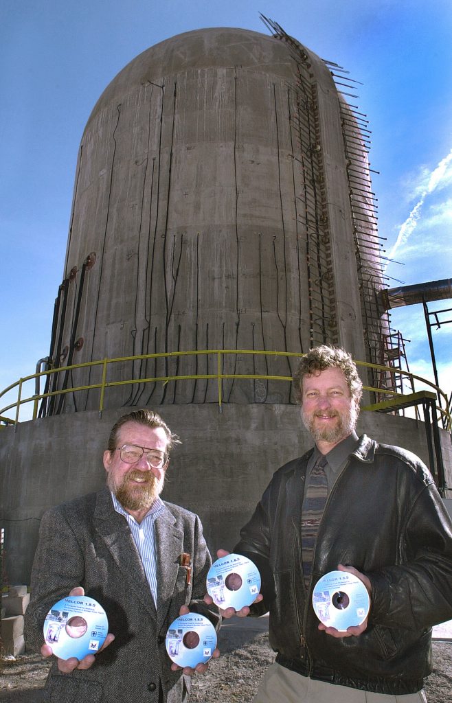 Sandia National Laboratories researchers Randy Cole (left) and Randy Gauntt with copies of MELCOR 1.8.5. Behind them is a 1/4-scale model of a pre-stressed concrete containment vessel used by Sandia recently to gather the type of experimental data about nuclear power reactors that MELCOR factors in when it models the progression of a severe accident at a power plant.