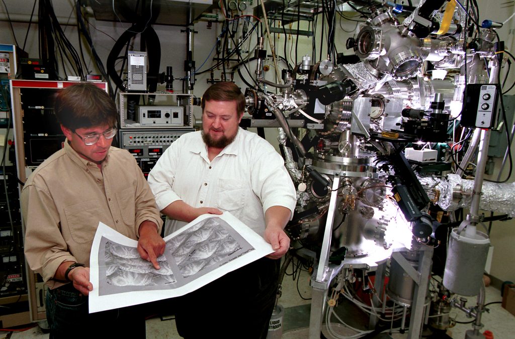 FORMATION OF QUANTUM DOTS -- Sandia's Jerry Floro, left, and John Hunter examine an atomic force micrograph image of semiconductor quantum dots. Using novel probes developed at Sandia, they have found that quantum dots repel each other. Quantifying the repulsion may help in turning assemblages of quantum dots into future solid-state lasers.