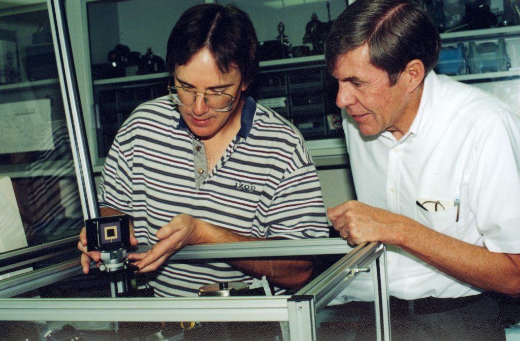 REMOTE SENSORING -- Sandia's Mike Sinclair (left) and Mike Butler prepare to put the dime-size Polychromator remote sensor chip into a testing unit.