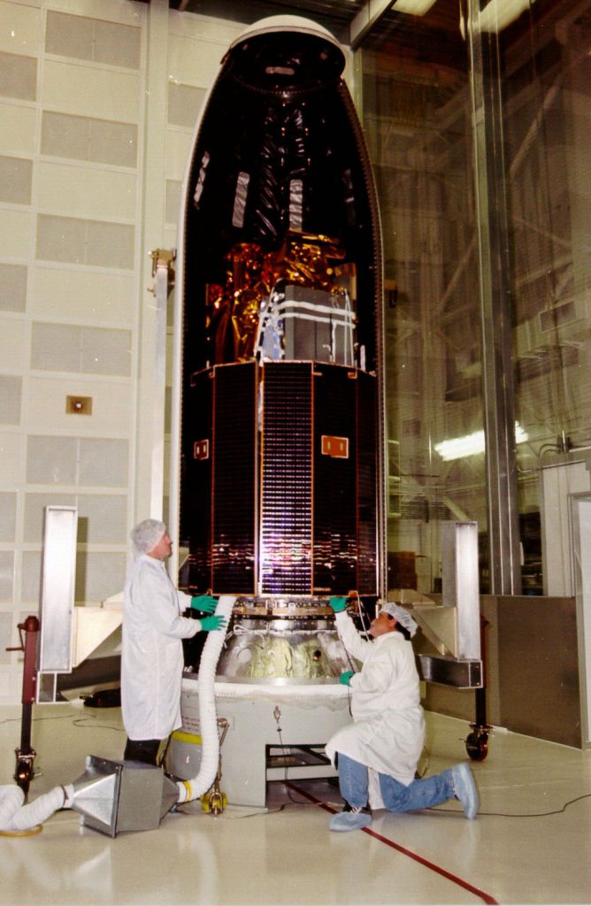 PAYLOAD PAYOFF -- Sandia engineers Chuck Looney (left) and Dennis Gutierrez make last-minute checks of the solar arrays on the Multispectral Thermal Imager (MTI) satellite at the Payload Processing Facility at Vandenberg Air Force Base, Calif., prior to encapsulating the satellite in preparation for launch scheduled for early Sunday morning, March 12. Half of the satellite's protective fairing (rocket nose cone) is visible in the background with its internal (black) thermal-acoustic blankets.