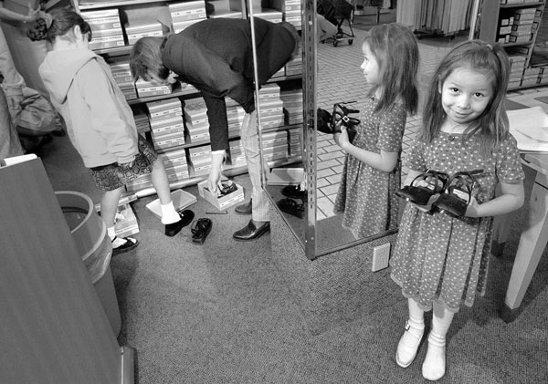 child in shoe store holds pair of shoes