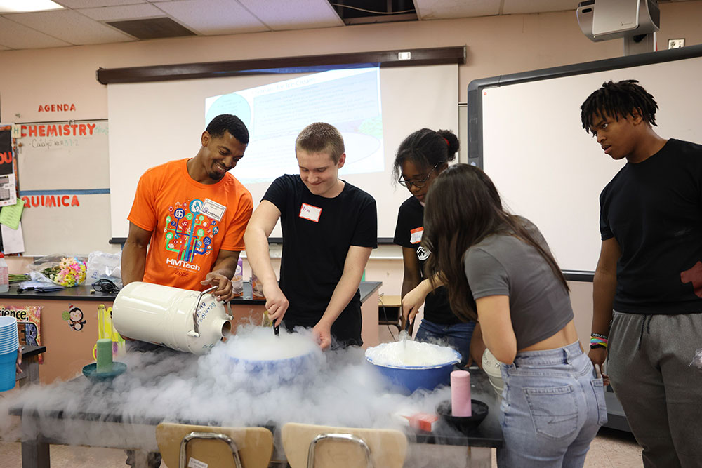 INTERACTIVE EXPERIMENTS — Sandia chemist and volunteer LaRico Treadwell, left, helps students make liquid nitrogen ice cream during HMTech.