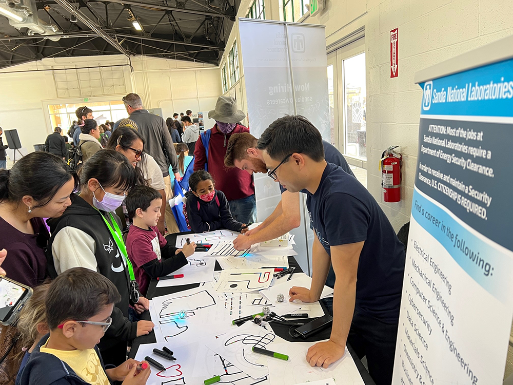 LEARNING TO CODE — Sandians, from right, Paolo Arguelles and Austin Scheck engage kids with an Ozobots coding-logic activity at the fifth annual Tri-Valley Innovation Fair on April 15. (Photo by Helena Jin)