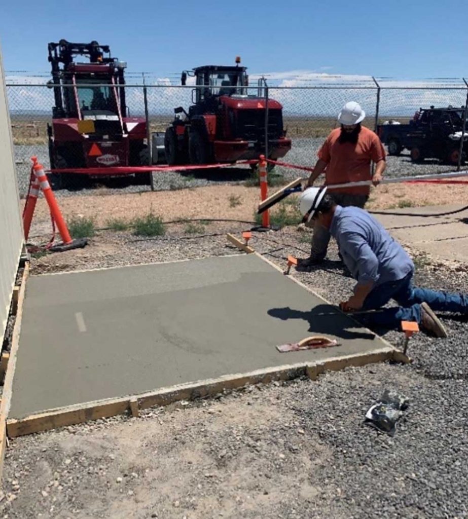 FOUNDATIONAL WORK — Carpenter tradesmen Kevin Pole, in blue, and laborer Fernando Marquez lay concrete. Kevin and Fernando are members of the In-House Construction team. (Photo courtesy of Lyndsy Ortiz)