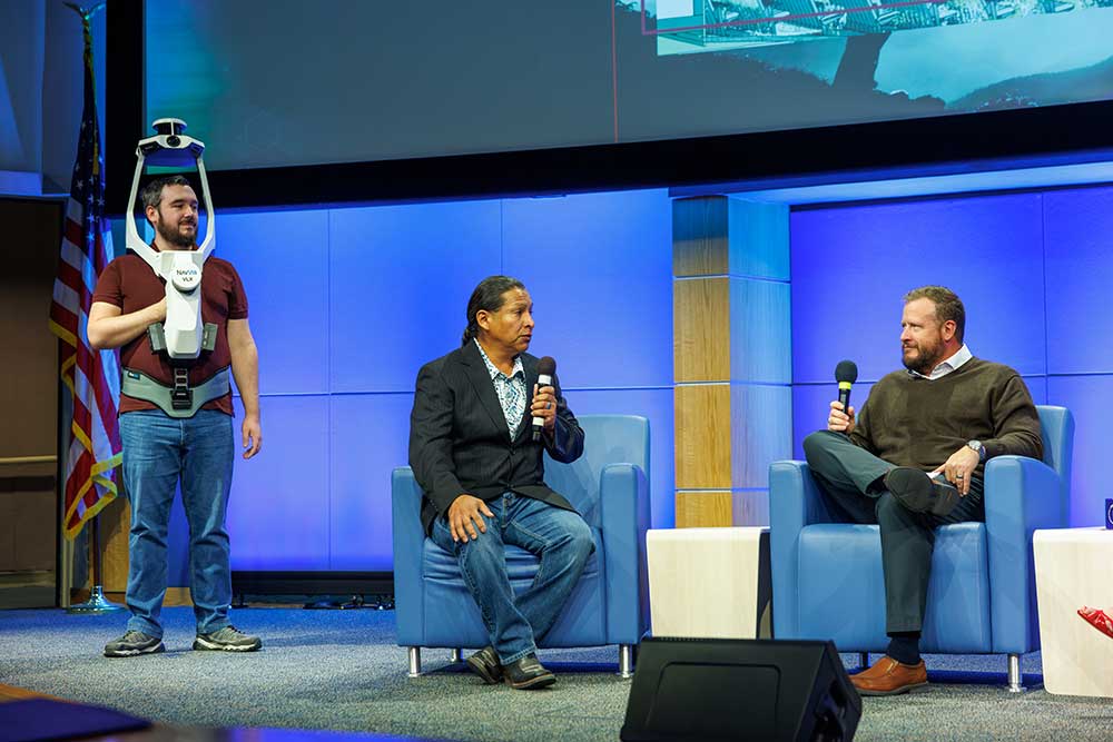 3D SCANNER — From left, Cason Brazil, Robert Tsinnijinnie and Jeff Heath at the Goal Getters II event. Robert is talking about his work getting Sandia to adopt the LiDAR scanning backpack technology, pictured here. (Photo by Bret Latter)