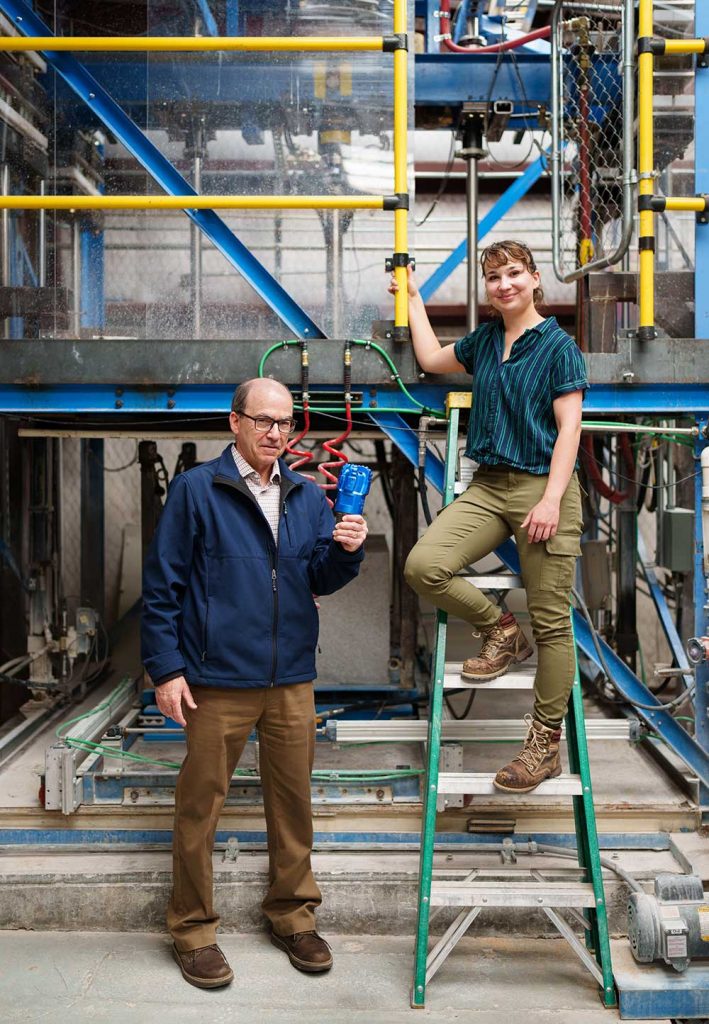 BETTER BITS FOR HARD ROCK — Sandia mechanical engineers David Raymond, left, and Melanie Schneider pose in Sandia’s Hard Rock Drilling Facility with a polycrystalline diamond compact bit. They recently completed an analysis on bit performance for geothermal well drilling. (Photo by Craig Fritz)